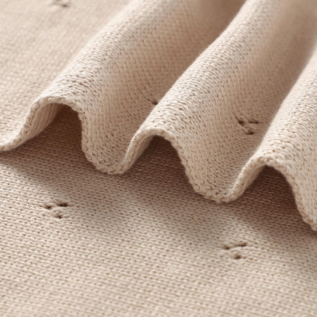 Close-up of beige fabric with visible texture and small holes.